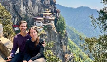 Couple with a view of a monastery on a cliff.
