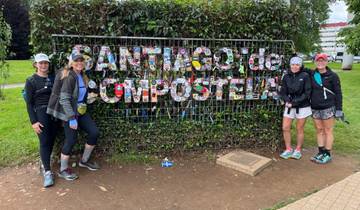 Group posing in front of Santiago de Compostela sign with colorful tiles.