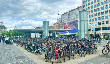 City square with numerous bicycles parked, modern architecture.