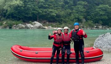 Three people posing with thumbs up by a red raft.