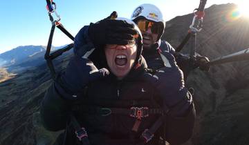 Two people making funny expressions while paragliding.