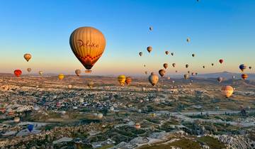 Colorful hot air balloons in the sky over a rocky landscape during sunrise.