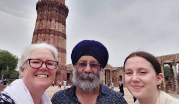 Three people posing in front of a historical tower.