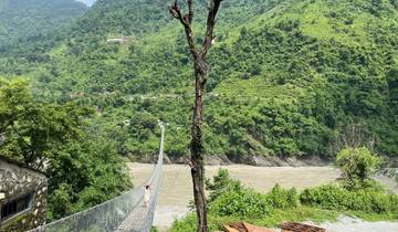 Person crossing a suspension bridge over a river.