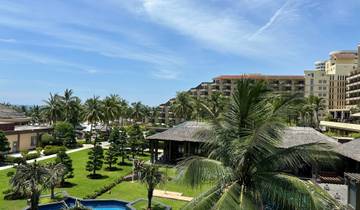 Resort with palm trees and buildings by the sea.