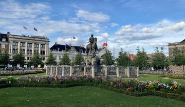 Equestrian statue surrounded by flowers in a city square.