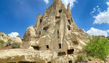 Ancient rock formations with carved openings under a clear blue sky.