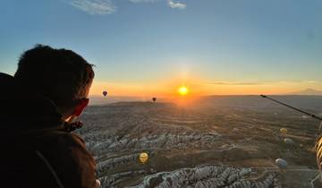 View from a hot air balloon over a rocky landscape during sunrise.