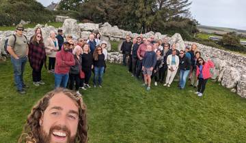 Group of people posing among old stone structures in a grassy field.