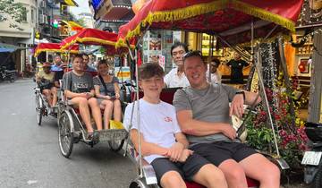 People enjoying a rickshaw ride through a busy street.