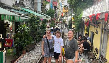 Three people posing on a railway track with buildings and vegetation surrounding them.