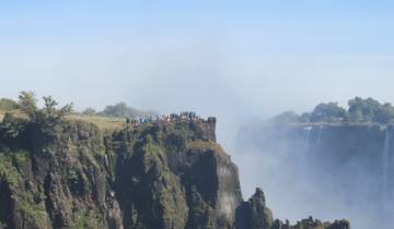 Cliffside view of Victoria Falls with tourists.