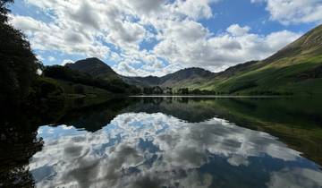 Serene lake with mountain reflections and cloudy sky.
