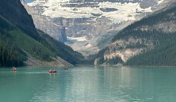 Canoes on a turquoise lake surrounded by mountains.