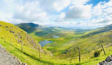 Panoramic view of lush green valley with mountains in distance.