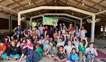 Large group of people posing joyfully inside a shelter.