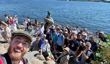 Group of tourists around the Little Mermaid statue by the water.
