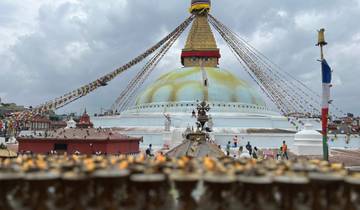 Stupa with colorful prayer flags and people in the background.