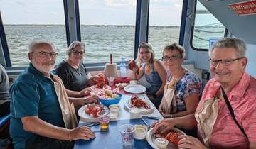 Group of people enjoying a lobster meal on a boat.