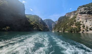 Wake trail of a boat on a river between steep cliffs.