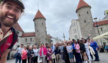 Group of people in front of historic stone buildings with towers.