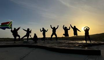 Silhouette of a group jumping with a South African flag at sunset.