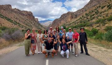 Group of tourists posing on a road with mountains in the background.
