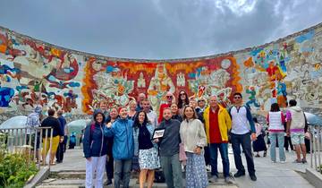 Group of people posing in front of a large mural.
