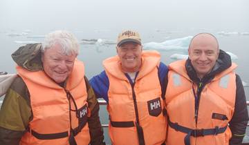 Three people in life jackets on a boat in icy waters.