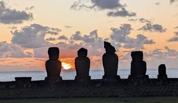 Several Moai statues by the sea during sunset.