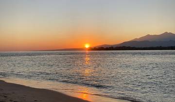 Beautiful sunset over the ocean with mountains in the distance.