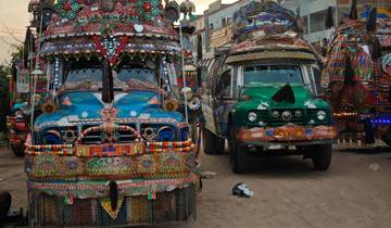 Heavily decorated trucks on a dirt road.