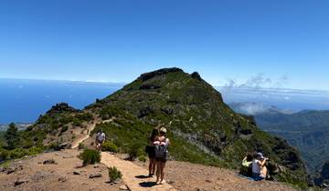 People hiking on a mountain trail with ocean view.