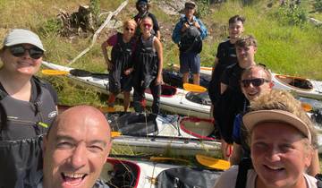 Group of people in kayaking gear posing with kayaks.