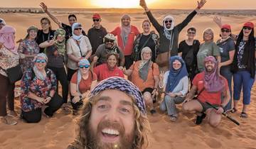 Group of people posing in a desert during sunset.
