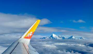 Airplane wing with a view of snow-covered mountains.