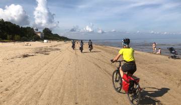 Cyclists riding along a sandy beach.