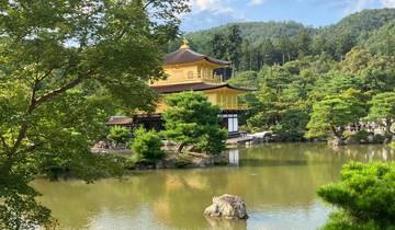 Golden pavilion at the edge of a pond with trees.