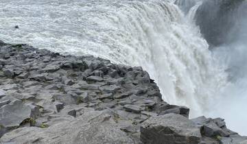 A close-up view of a powerful waterfall with rocky terrain.