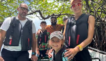 Group of people in life jackets on a boat ride through mangroves.