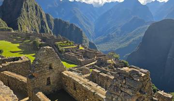 Machu Picchu ruins with visitors, surrounded by mountains.