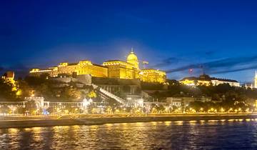 Illuminated historic building along a river at night.