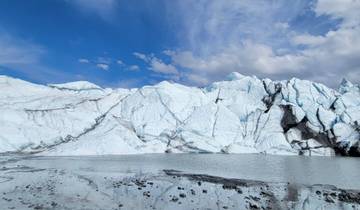 Panoramic view of a glacier reflecting in calm water.