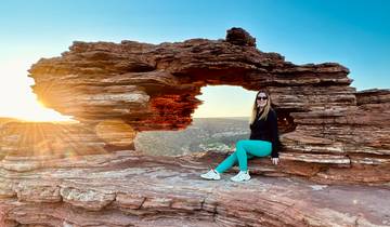 Person sitting in a rock formation with sunlight.