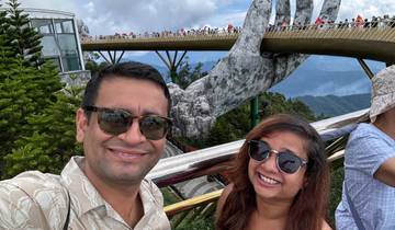 A couple posing in front of a bridge with large stone hands holding it.