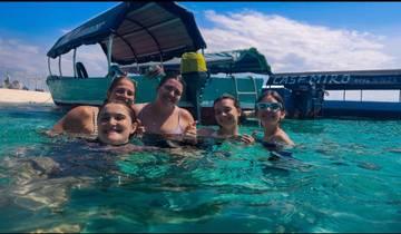 People swimming in clear blue water near a boat.