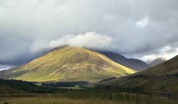 A mountain partially covered by clouds under a dramatic sky.