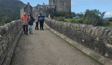 People walking across a stone bridge to a castle