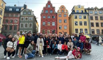 Large group of people posing in front of colorful buildings in a city square.