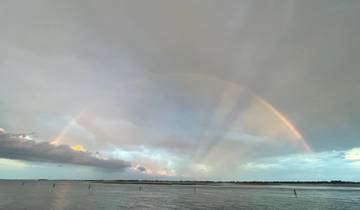 A rainbow over a body of water during cloudy weather.